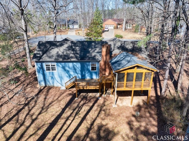 back of house featuring a deck, roof with shingles, and a chimney