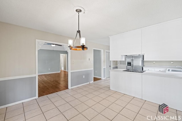 kitchen featuring light tile patterned floors, light countertops, white cabinetry, a sink, and stainless steel fridge with ice dispenser