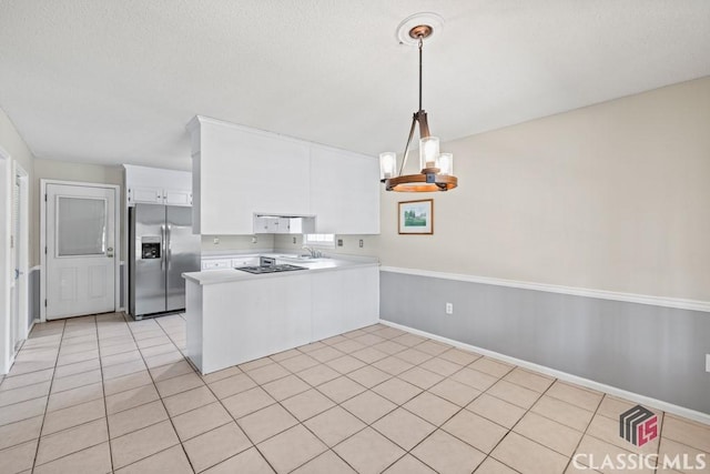 kitchen with light tile patterned floors, light countertops, white cabinets, stainless steel fridge, and a peninsula