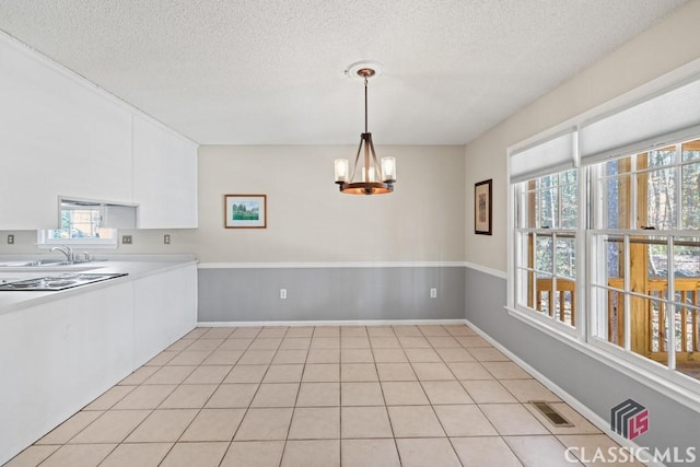 kitchen with pendant lighting, visible vents, an inviting chandelier, white cabinets, and a sink