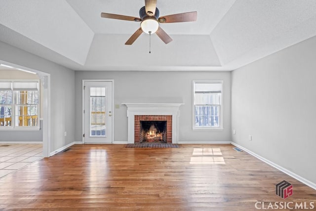 unfurnished living room with plenty of natural light, a fireplace, and a tray ceiling