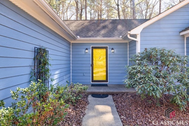 doorway to property with roof with shingles