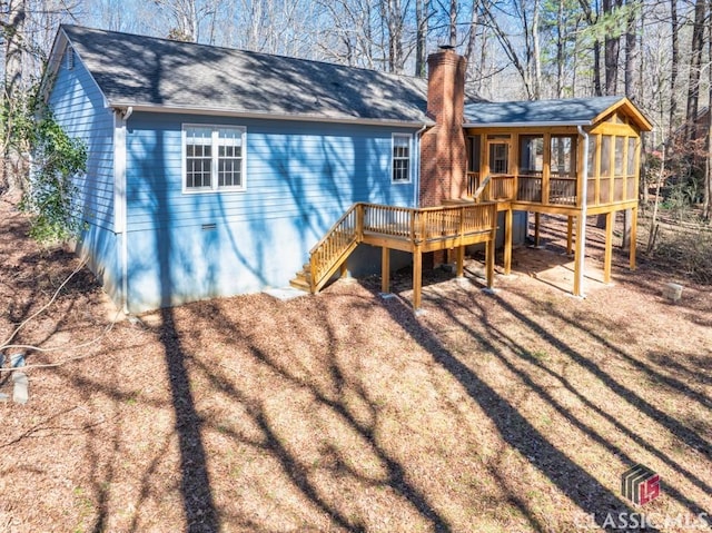 back of property with roof with shingles, a chimney, stairway, a sunroom, and a deck