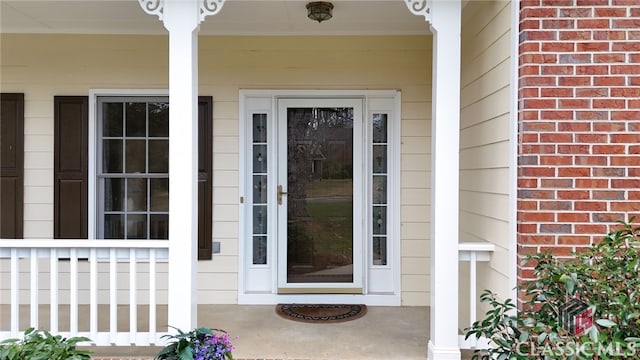 property entrance featuring a porch and brick siding