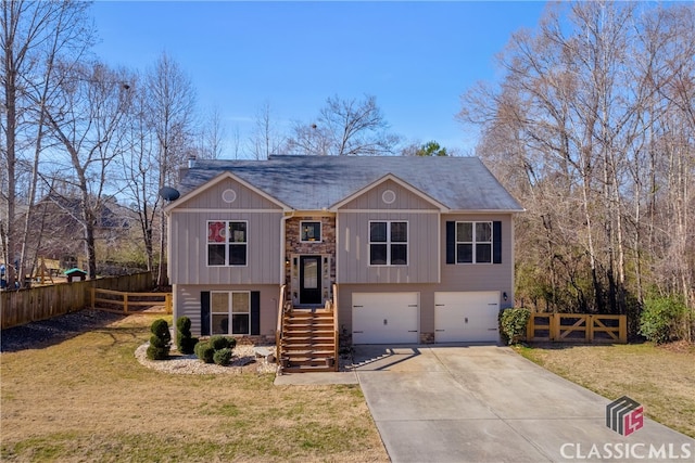 split foyer home featuring driveway, an attached garage, fence, and a front yard