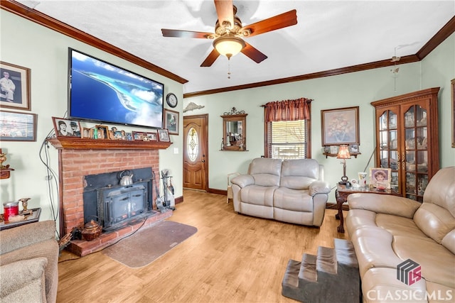 living area featuring ceiling fan, ornamental molding, light wood-type flooring, and a wood stove