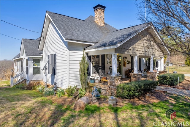 view of front of home with a shingled roof, a chimney, and a front yard