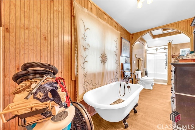 full bathroom featuring wood finished floors, a freestanding tub, and wooden walls