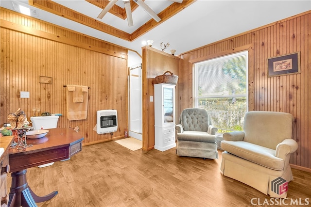 living area with heating unit, a ceiling fan, wooden walls, wood finished floors, and baseboards