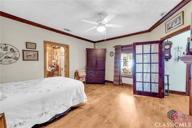 bedroom with visible vents, ornamental molding, a textured ceiling, light wood-type flooring, and baseboards