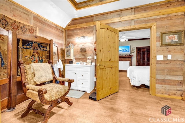 living area with a ceiling fan, lofted ceiling, wood walls, and light wood finished floors