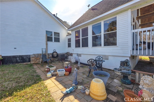 back of house with crawl space, roof with shingles, and a patio