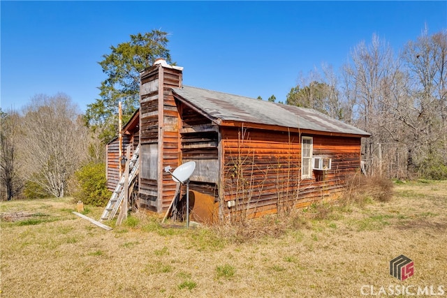 view of side of property featuring a chimney and an outdoor structure