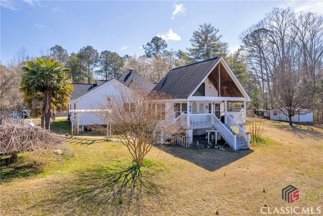 rear view of property with covered porch, a yard, and stairway