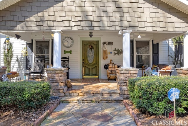 doorway to property featuring covered porch and a shingled roof