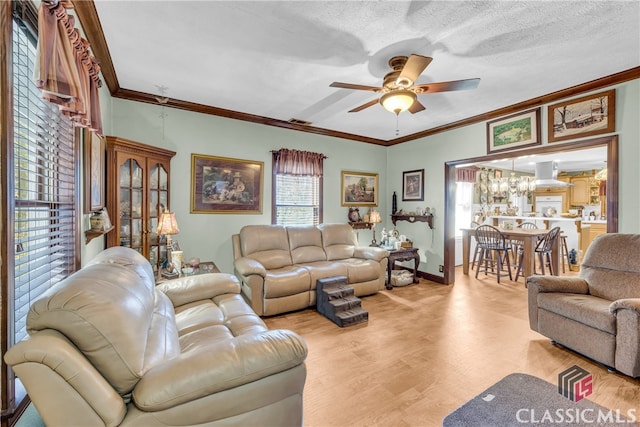 living room with baseboards, visible vents, a ceiling fan, wood finished floors, and crown molding