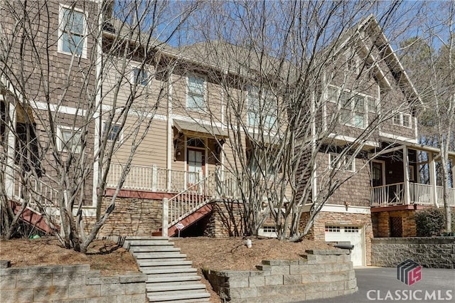 view of property featuring a garage, driveway, and stairs