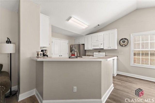 kitchen featuring visible vents, range with electric cooktop, white microwave, freestanding refrigerator, and vaulted ceiling