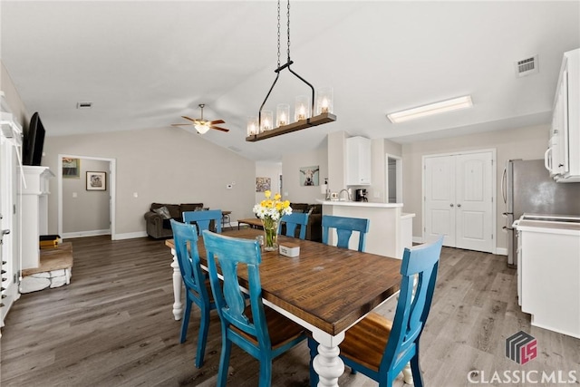 dining space featuring ceiling fan, visible vents, vaulted ceiling, and wood finished floors