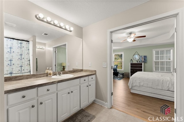 ensuite bathroom with ceiling fan, wood finished floors, vanity, visible vents, and ensuite bath