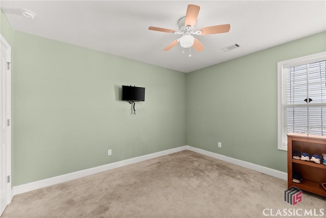 carpeted spare room featuring baseboards, visible vents, and a ceiling fan