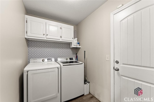 laundry area featuring a textured ceiling, separate washer and dryer, dark wood-type flooring, and cabinet space