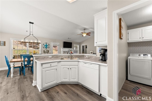 kitchen with white cabinetry, white dishwasher, a sink, washer / dryer, and a peninsula