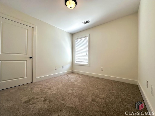 empty room with carpet, visible vents, and baseboards