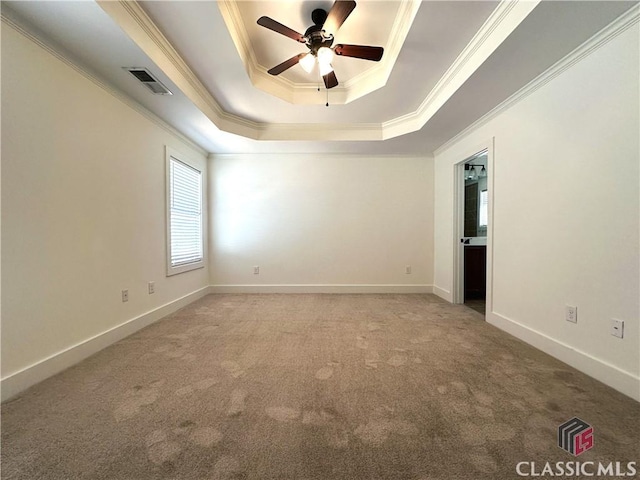 carpeted empty room with a tray ceiling, crown molding, visible vents, a ceiling fan, and baseboards