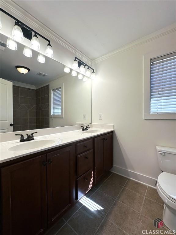 full bath featuring double vanity, a sink, toilet, and crown molding