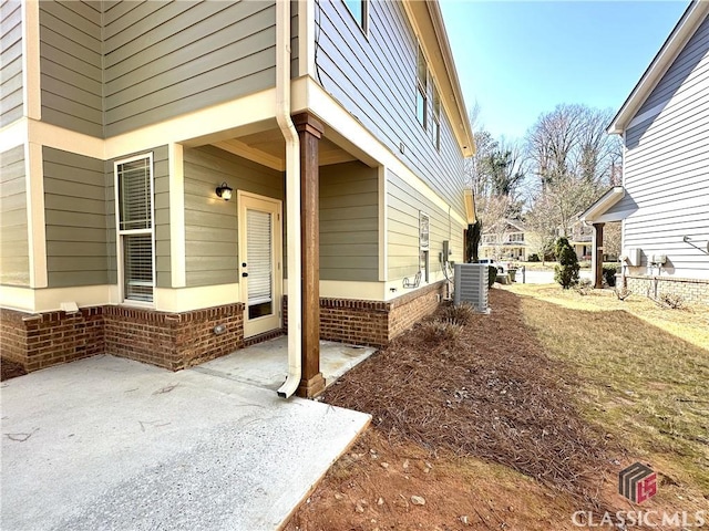 exterior space with a patio area, central AC, and brick siding