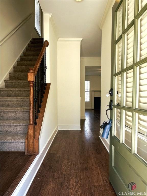 interior space with stairway, crown molding, baseboards, and dark wood-type flooring