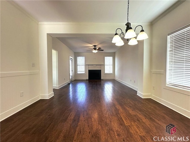 unfurnished living room with ceiling fan with notable chandelier, dark wood-style flooring, a fireplace, baseboards, and ornamental molding