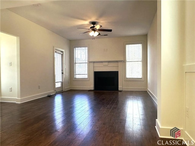 unfurnished living room featuring a fireplace, dark wood finished floors, a ceiling fan, and baseboards