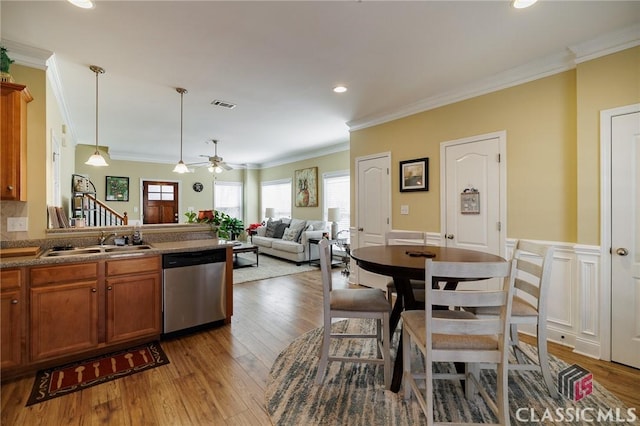 kitchen with brown cabinets, visible vents, ornamental molding, a sink, and dishwasher