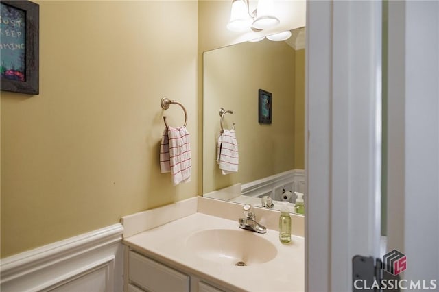 bathroom featuring a wainscoted wall, vanity, and a decorative wall