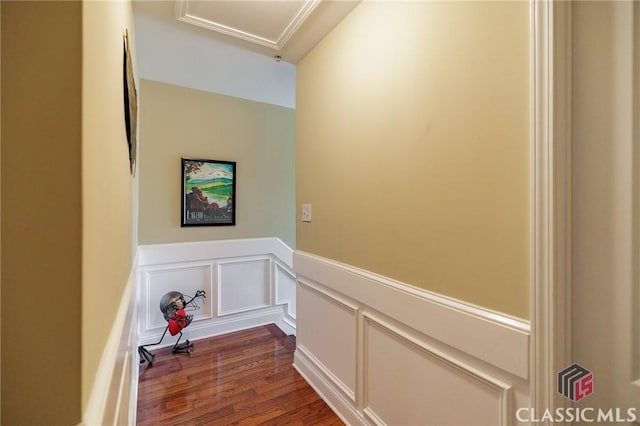 corridor with attic access, a wainscoted wall, dark wood finished floors, and a decorative wall