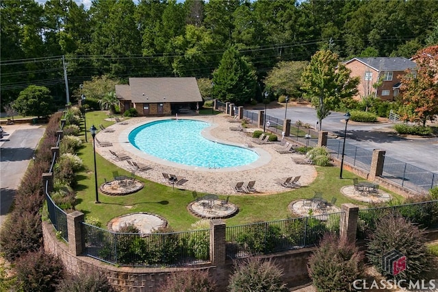 pool with a patio area, fence, and a lawn