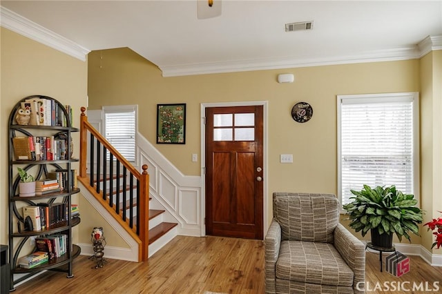 entryway featuring ornamental molding, stairway, light wood-type flooring, and visible vents