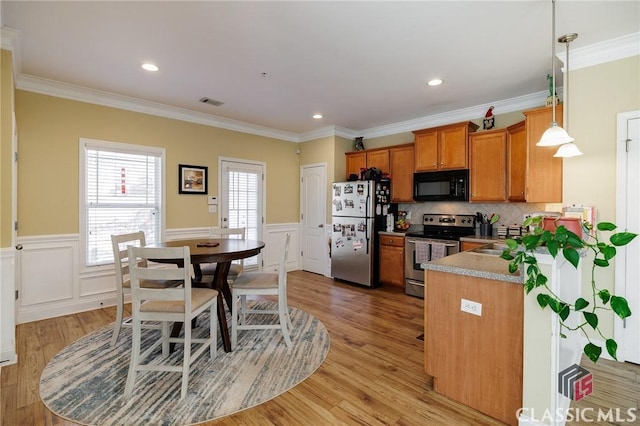 kitchen featuring brown cabinets, light wood-style flooring, stainless steel appliances, and wainscoting