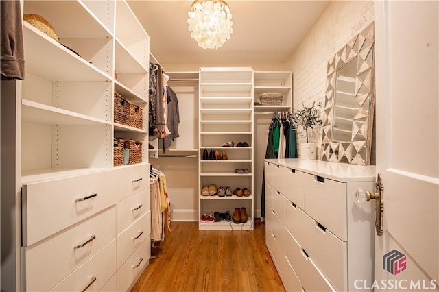 spacious closet featuring a chandelier and light wood-style flooring