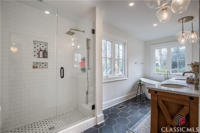 bathroom featuring double vanity, baseboards, tile patterned flooring, a shower stall, and a sink