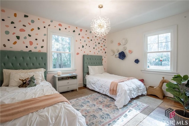 bedroom with multiple windows, light wood-style flooring, and a notable chandelier