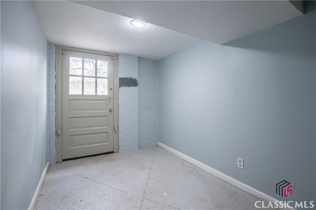 doorway featuring baseboards and speckled floor