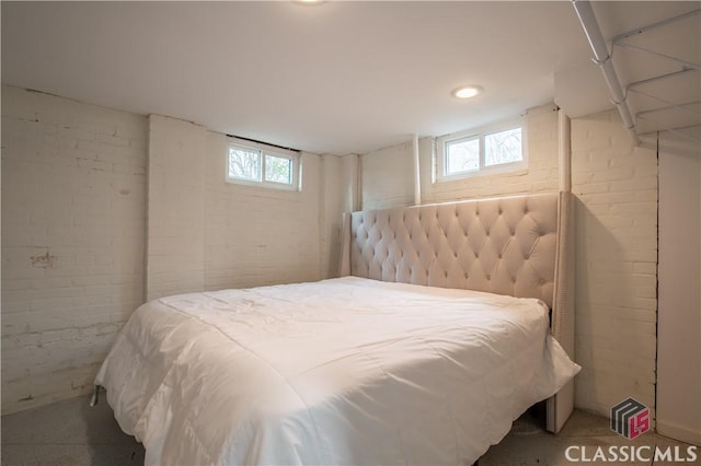 bedroom with multiple windows and brick wall