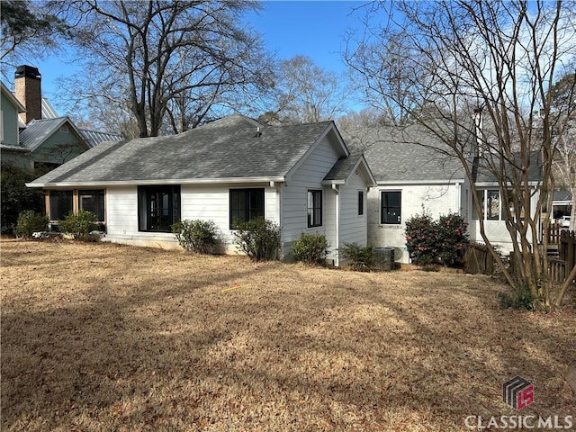 view of front of home featuring a shingled roof, a front lawn, and central AC unit