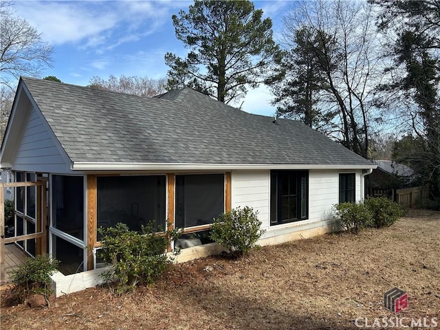 exterior space with a sunroom and roof with shingles