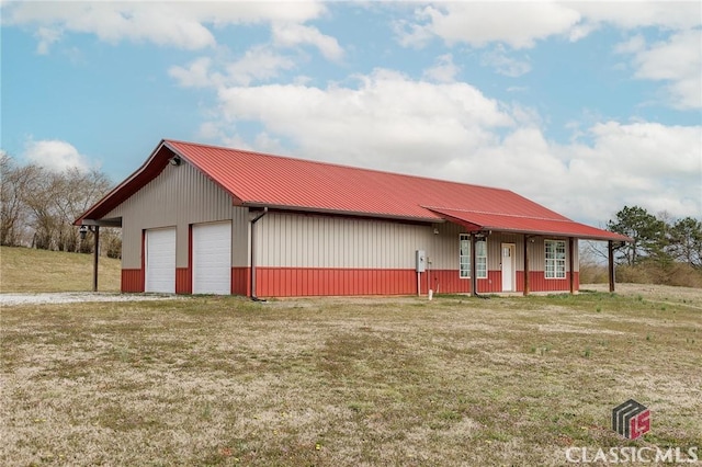 view of front facade with metal roof, a detached garage, a front lawn, and an outdoor structure