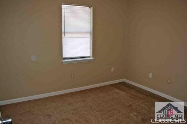 spare room featuring carpet floors and baseboards