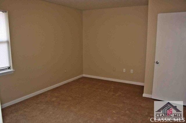 empty room featuring carpet and baseboards